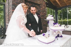 braut und bräutigam schneiden hochzeitstorte bei ihrer hochzeitsfeier