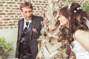braut und bräutigam stehen an einer palme und tauschen zärtlichen Blicke aus während der sie fotografiert werden