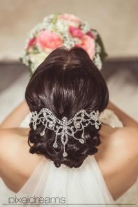 brautfrisur mit brautschleier von oben mit sicht auf das diadem und dem brautstrauß. das brautkleid ist schulterfrei