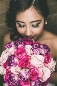wundervolle pose der Braut mit ihrem Brautstrauß in rosa lila und pink, Braut Make up künstliche Wimpern und Brautfrisur im perfekten Einklang