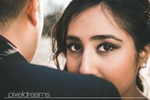 Braut posiert vor der Kamera an der Schulter des Bräutigam - perfektes Braut Make up und Brautfrisur - Hochzeitsfotos von Pixeldreams in Köln, Bonn, Düsseldorf, Bochum, Essen und deutschlandweit