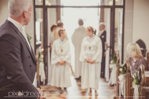 Bäutigam wartet auf seine Braut. Er sieht sie zum ersten mal im Brautkleid. Die Hochzeit/ Trauung findet in der St. Antonius Kirche in Swisttal statt. Hochzeitsfotograf Pixeldreams ist Deutschlandweit unterwegs.