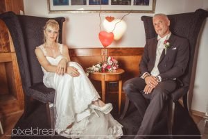 Braut und Bräutigam posen sitzend vor dem Hochzeitsfotografen für ihre Hochzeitsfotos.