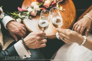 Braut und Bräutigam stoßen mit Sekt an. Hochzeitsfoto aus der Vogelperspektive. Trauringe und Brautstrauß.