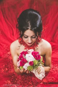 Henna Fotos, Kına Resimleri – Braut mit Blumenstrauß/ Brautstrauß im Hennakleid, rotem Ballkleid aus der Vogelperspektive fotografiert. Entfesselt geblitzt mit einer Softbox. Rotes Ballkleid kommt schön zur Geltung. Brautfrisur und Braut Make Up/ Abend Make Up kommen ebenfalls schön zur Geltung. Braut schaut verträumt auf ihr Brautstrauß. Henna Foto