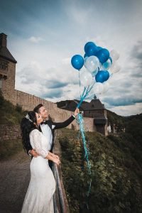 Braut und Bräutigam halten Helium Hochzeits-Ballons am umliegenden Pfad von Burg Altena