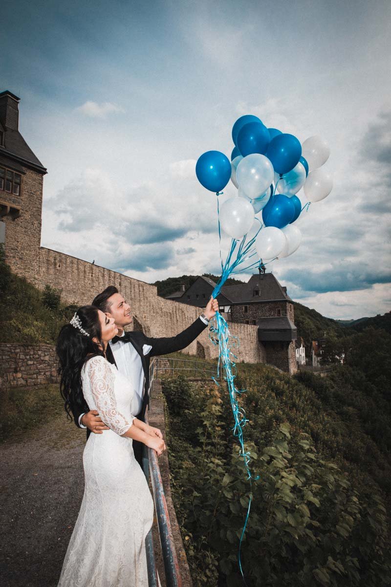 Braut und Bräutigam halten Helium Hochzeits-Ballons am umliegenden Pfad von Burg Altena