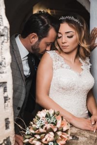 Hochzeitsbild eines türkischen Brautpaares. Türkischer Hochzeitsfotograf Fotografiert das Paar in einer sinnlichen Pose. Bräutigam küsst Braut auf die Schulter. Kreatives Hochzeitsfoto.