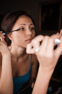Hochzeitsfoto einer Braut beim Getting dressed. Braut legt selbst Hand an und tuscht ihre Wimpern. Natürliches Hochzeitsfoto vom Hochzeitstag.