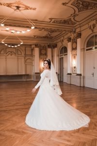 Hochzeitsfoto entstanden in der Stadthalle Wuppertal. Wundervolle Location mit viel Stuck, Schmuck und edler Einrichtung. Braut präsentiert ihr Brautkleid von hinten. Kreatives Hochzeitsfoto vom Hochzeitsfotografen Pixeldreams.