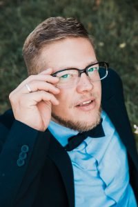 Hochzeitsbild vom Bräutigam aus erhöhter Perspektive. Bräutigam richtet seine Brille und schaut dabei in die Kamera. Kreatives Hochzeitsfoto mit Ringlicht im Einsatz.