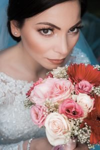 Hochzeitsbild einer Braut mit Braut Strauß in der Hand. Sie schaut von unten nach oben in die Kamera. Ring Licht kam als Beleuchtung zum Einsatz. Ein wunderschönes und kreatives Hochzeitsfoto.